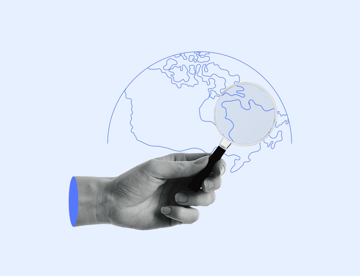 A hand holding a magnifying glass over a stylized drawing of the globe, emphasizing the focus on global interactions.