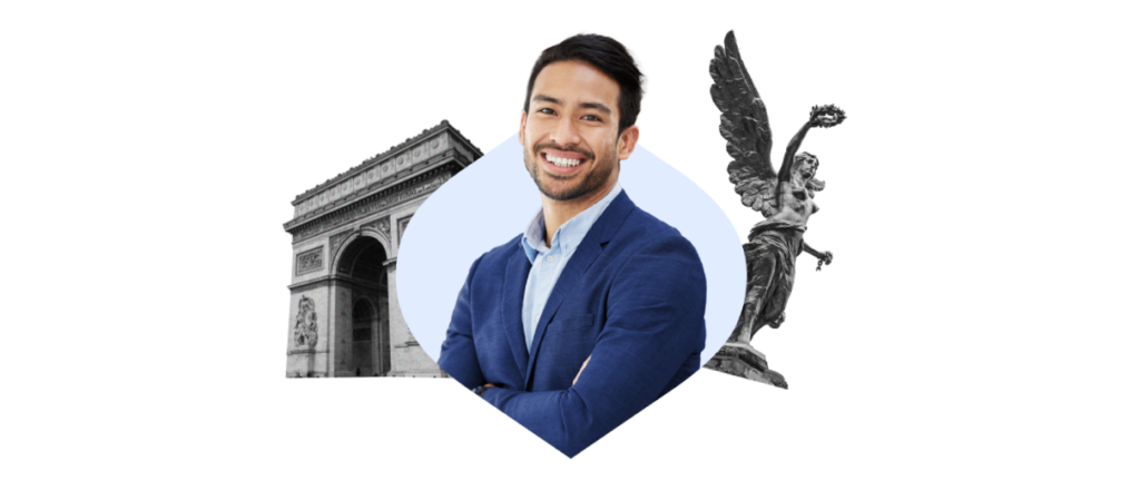 A confident man in a blue blazer smiling, with the Arc de Triomphe on his left and a statue of an angel wielding a sword on his right, symbolizing a blend of historical architecture and modern style.