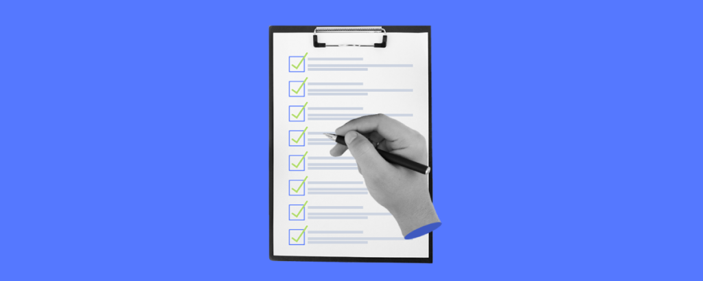 A hand holding a pen and ticking off items on a checklist. The clipboard with the checklist is set against a bold blue background, highlighting the action of completing tasks or confirming criteria