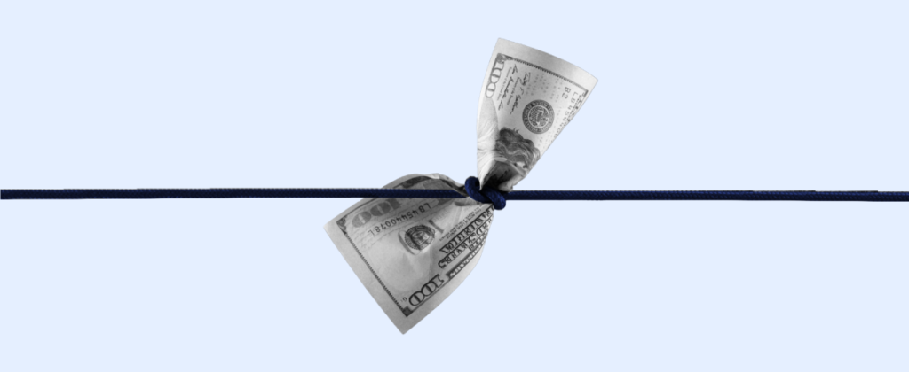 The image features a single hundred-dollar bill, folded into a "V" shape, and appearing to be tied or pinched at the center by a tight blue rope against a light background, suggesting a concept of money being constrained or secured.
