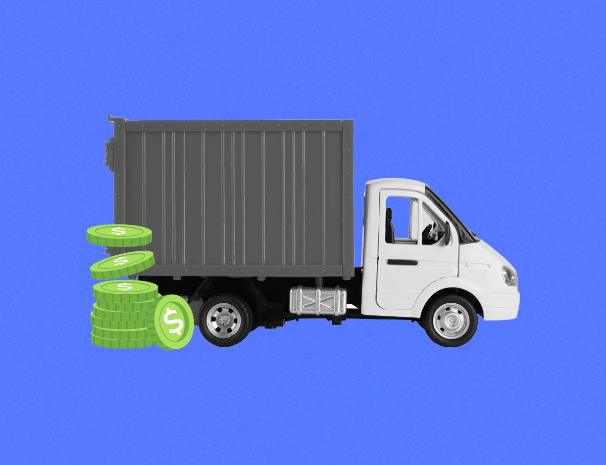 Camión de carga blanco con la parte trasera del contenedor gris, a su lado, pilas de monedas de dólar simbolizan financiamiento.