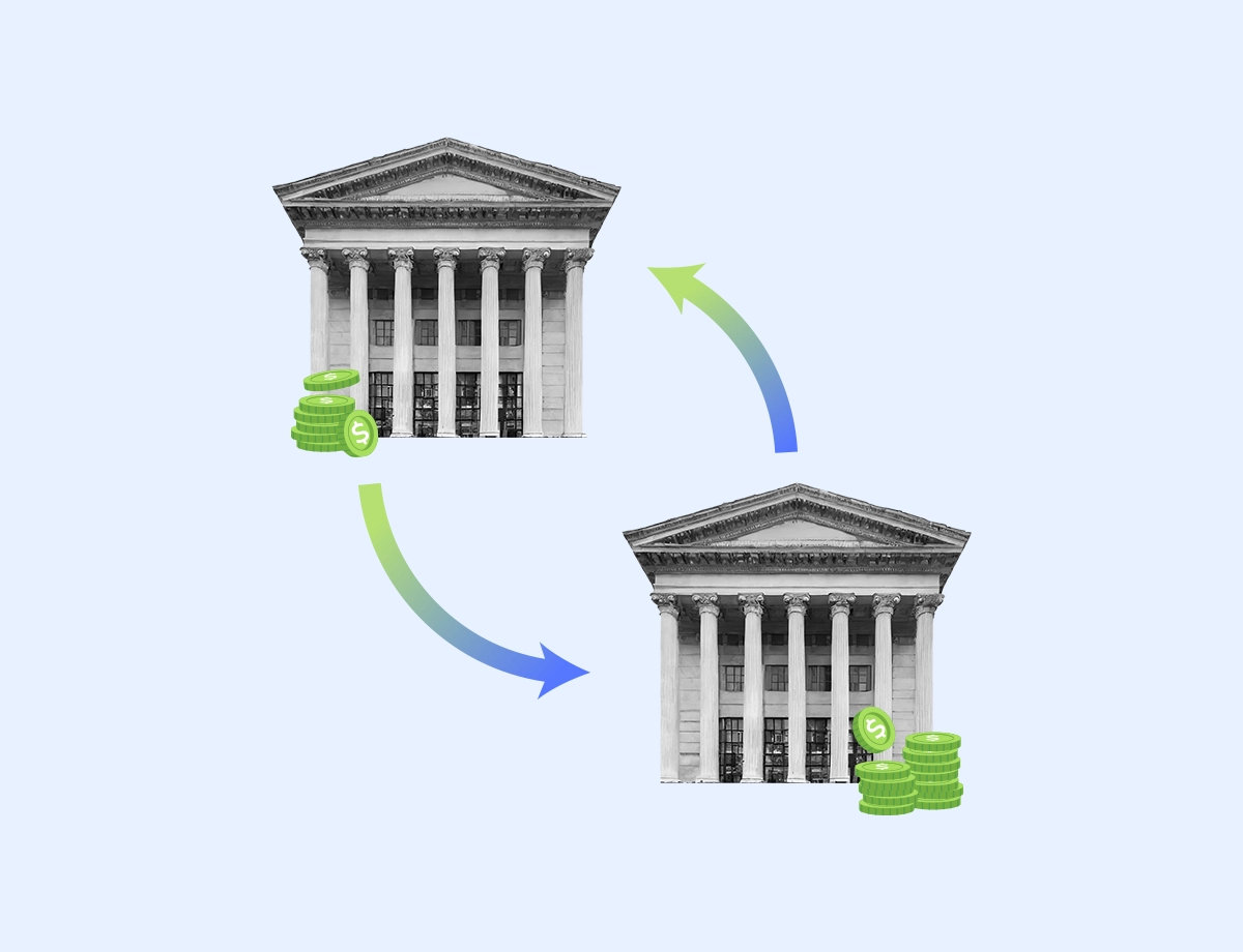 This image features two classical bank building facades in greyscale, symbolizing traditional banking institutions. Between them are green arrows forming a cycle, with stacks of coins bearing the dollar sign at each end.